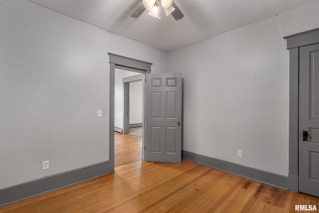 empty room featuring ceiling fan, light wood-type flooring, and a baseboard radiator