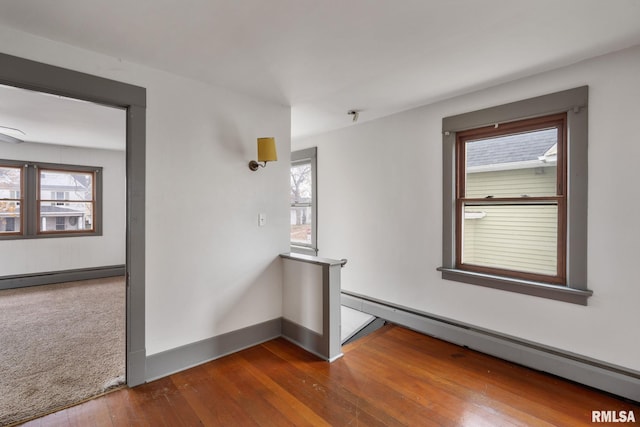 spare room with hardwood / wood-style floors and a baseboard heating unit