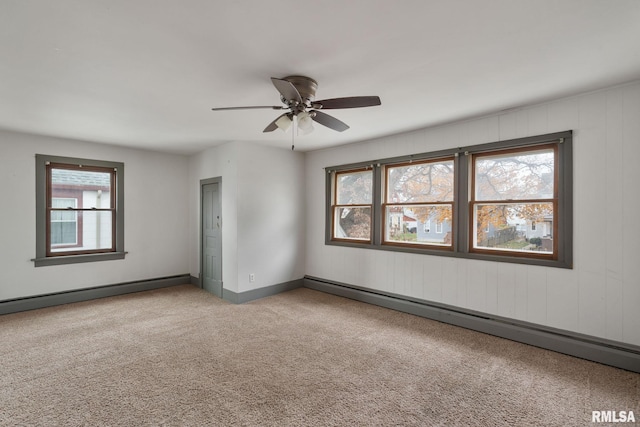 carpeted empty room featuring baseboard heating, a wealth of natural light, and ceiling fan