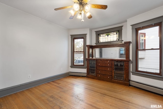 empty room featuring ceiling fan, a baseboard radiator, and light hardwood / wood-style flooring