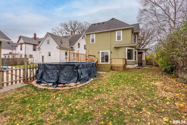 rear view of property featuring a pool side deck and a yard