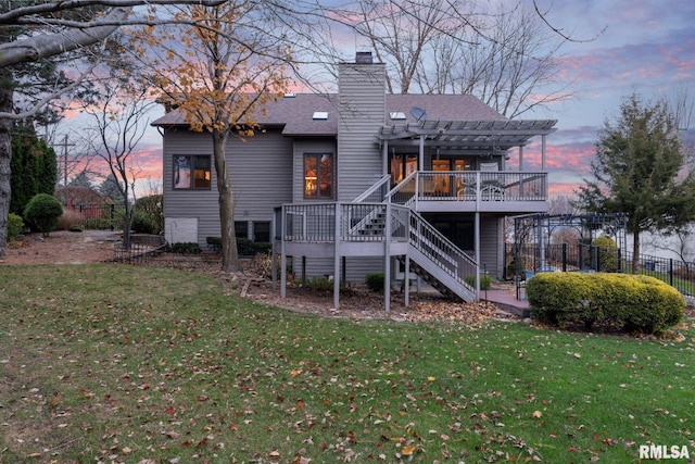 back house at dusk featuring a pergola, a lawn, and a wooden deck