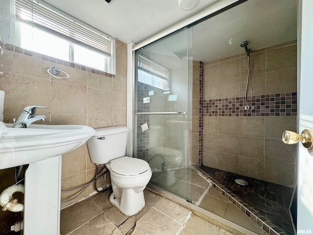 bathroom featuring tiled shower, toilet, and tile walls