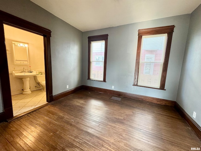 unfurnished bedroom featuring hardwood / wood-style flooring and connected bathroom