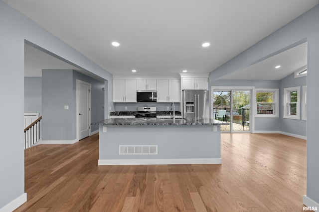 kitchen featuring light hardwood / wood-style flooring, sink, white cabinetry, dark stone countertops, and stainless steel appliances