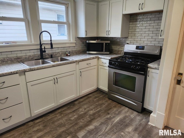 kitchen with white cabinetry, sink, dark hardwood / wood-style flooring, decorative backsplash, and appliances with stainless steel finishes