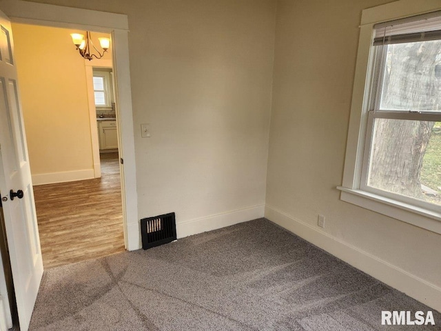 empty room featuring a chandelier, wood-type flooring, and plenty of natural light