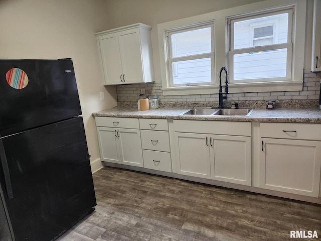 kitchen with black refrigerator, white cabinetry, dark wood-type flooring, and sink