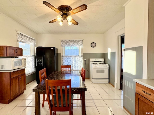 dining space featuring a healthy amount of sunlight, light tile patterned floors, baseboards, and a ceiling fan