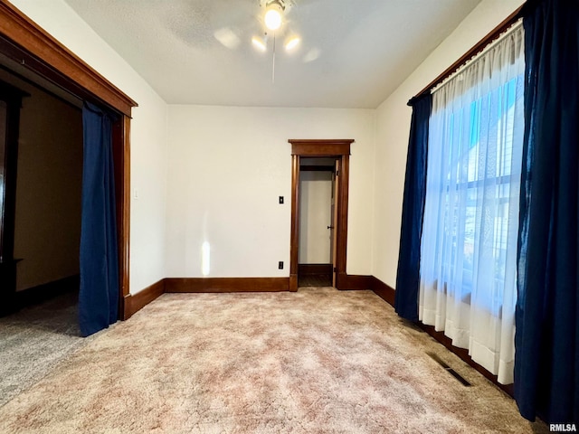 carpeted spare room featuring visible vents, a textured ceiling, and baseboards