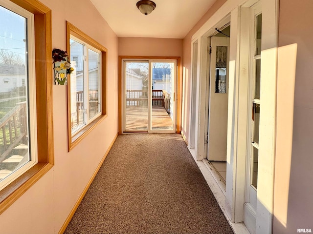 hallway featuring light carpet and baseboards