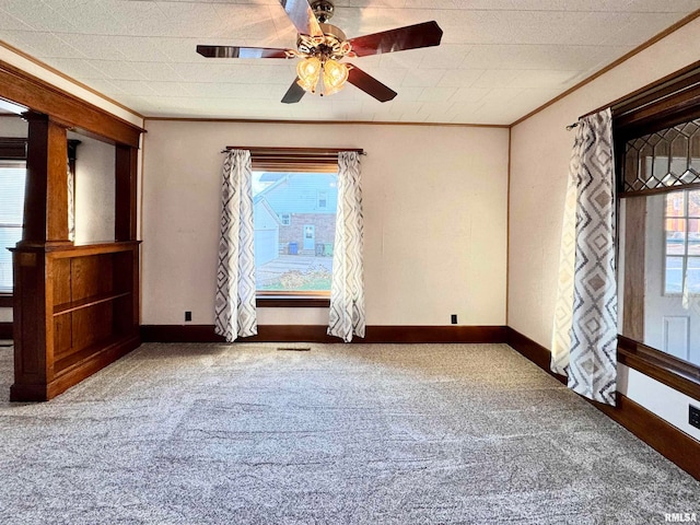 carpeted empty room with baseboards, ornamental molding, and a ceiling fan