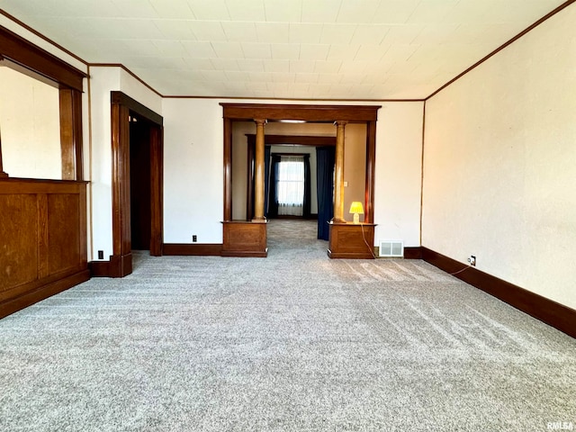 empty room featuring carpet floors, visible vents, crown molding, and baseboards