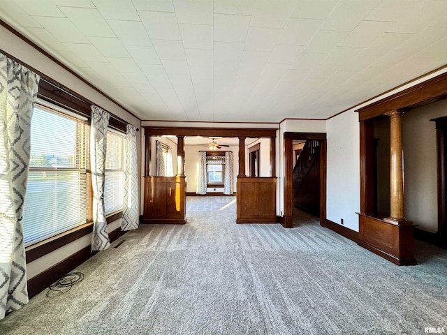 carpeted spare room featuring baseboards, crown molding, and ornate columns