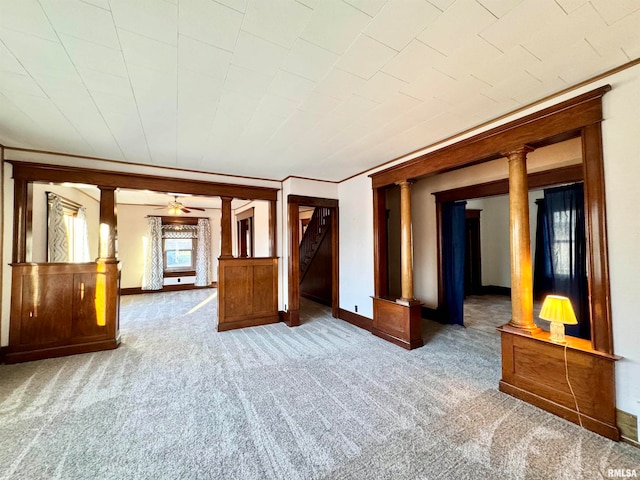 carpeted spare room with decorative columns and baseboards