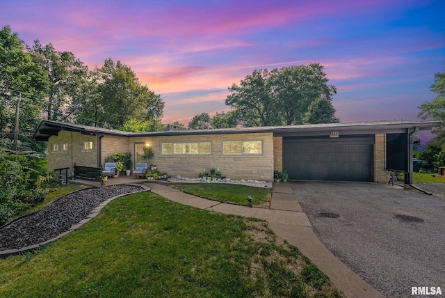 single story home featuring a garage and a yard