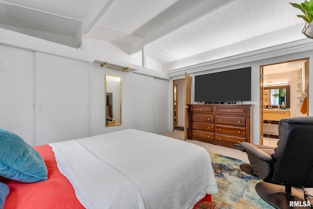 bedroom featuring vaulted ceiling with beams, a closet, and ensuite bath