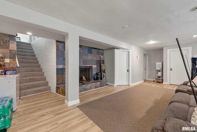 living room featuring a tile fireplace and light hardwood / wood-style flooring