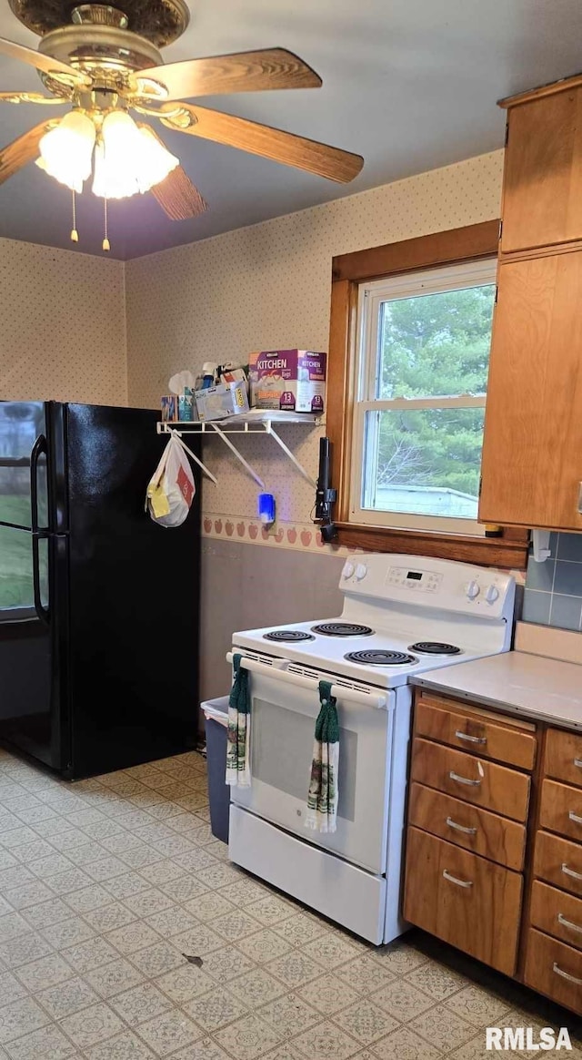 kitchen featuring ceiling fan, black refrigerator, and white range with electric stovetop