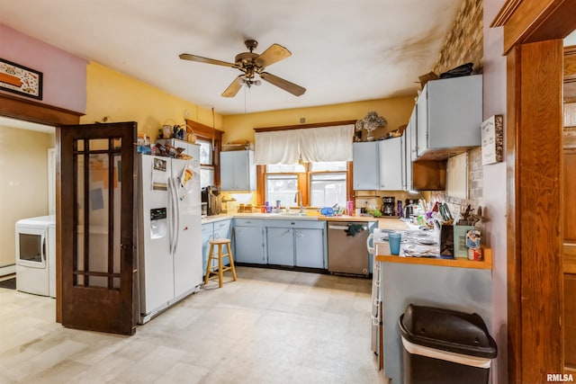 kitchen with white refrigerator with ice dispenser, sink, stainless steel dishwasher, ceiling fan, and washer / dryer