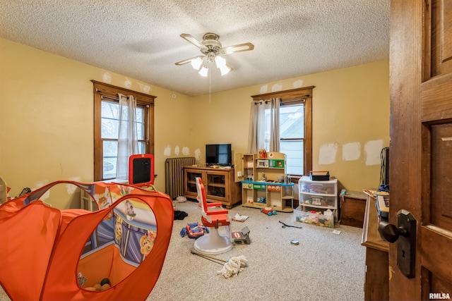 playroom with carpet flooring, radiator, ceiling fan, and a textured ceiling