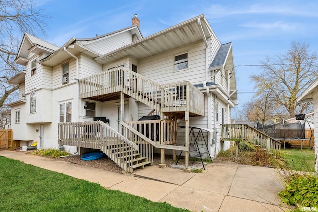 rear view of property with a patio area, a deck, and a trampoline