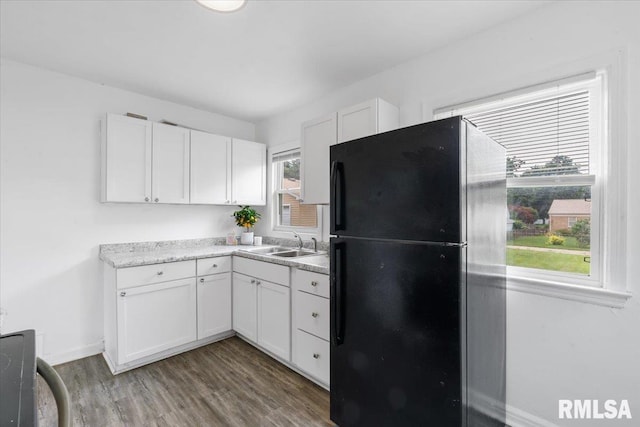 kitchen featuring white cabinets, black fridge, and a healthy amount of sunlight