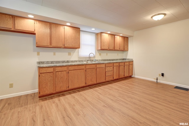 kitchen featuring light hardwood / wood-style floors, crown molding, and sink