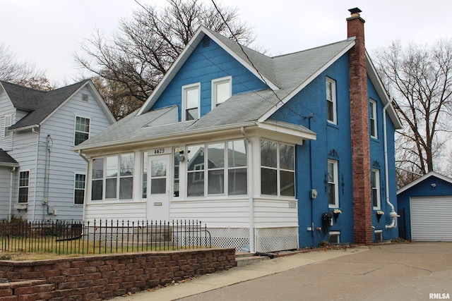 view of front facade with a sunroom, an outdoor structure, and a garage