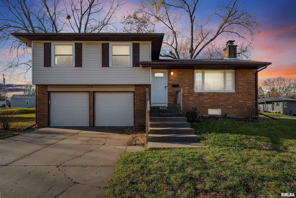 tri-level home with a garage and a lawn