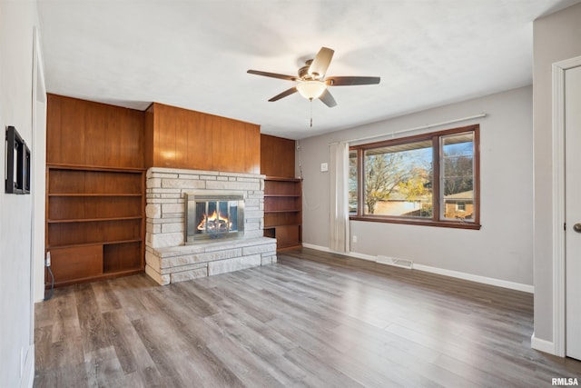 unfurnished living room with a stone fireplace, ceiling fan, and hardwood / wood-style flooring