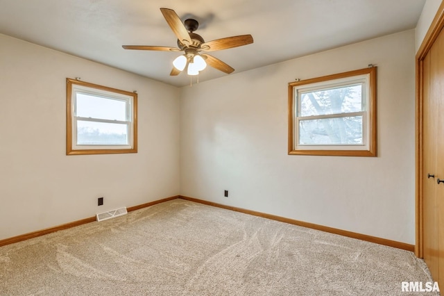 empty room featuring carpet floors, ceiling fan, and a healthy amount of sunlight