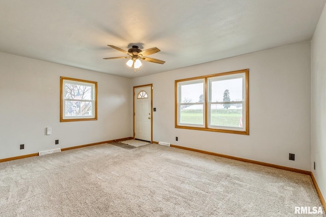 spare room with ceiling fan, light carpet, and a wealth of natural light