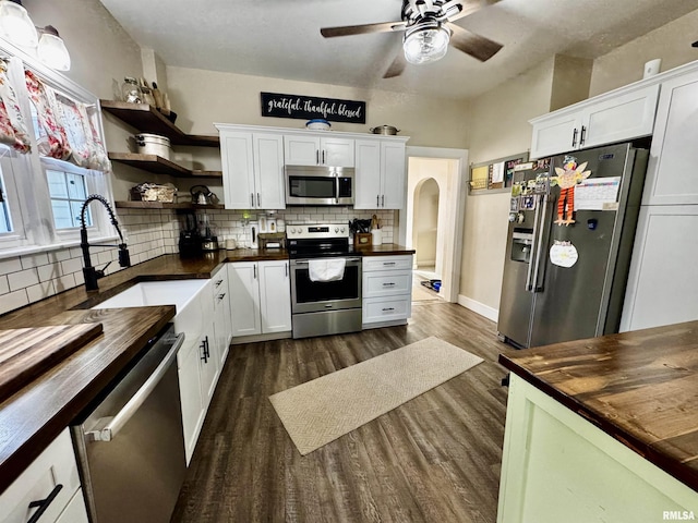 kitchen with sink, stainless steel appliances, dark wood-type flooring, wooden counters, and white cabinets