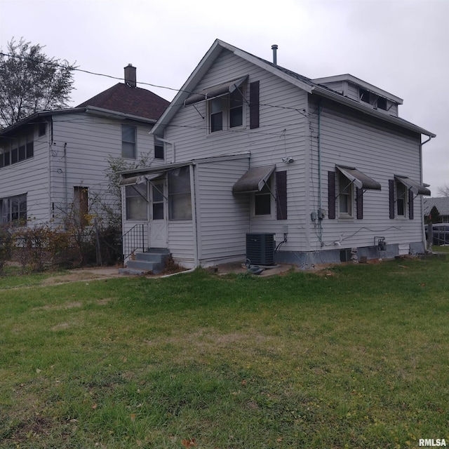 rear view of property featuring cooling unit and a lawn