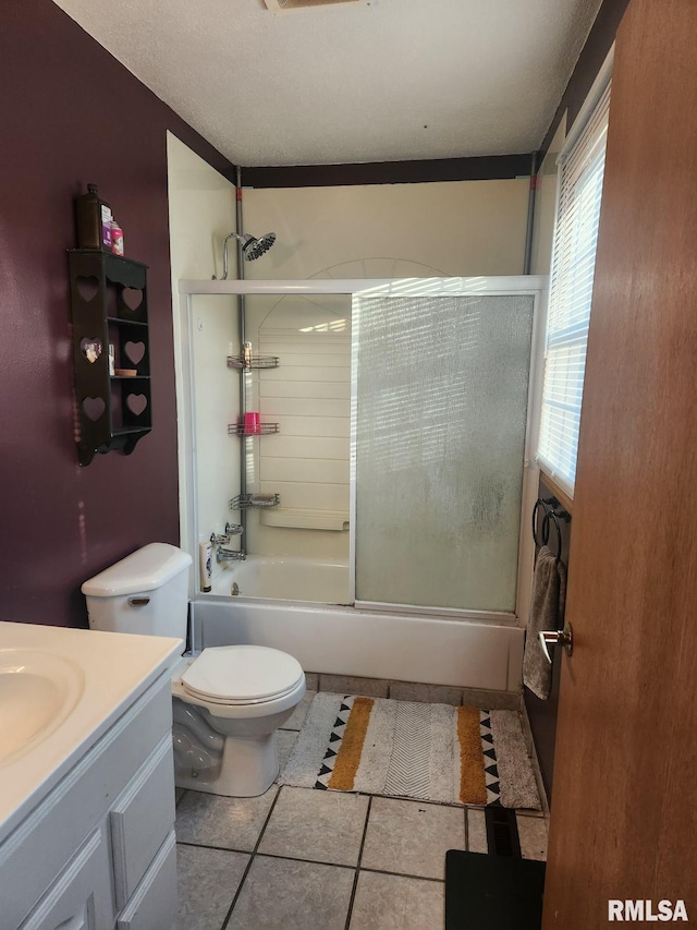 full bathroom featuring vanity, tile patterned floors, bath / shower combo with glass door, toilet, and a textured ceiling