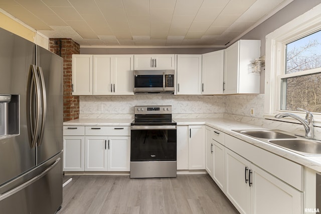 kitchen with sink, stainless steel appliances, white cabinets, and light wood-type flooring