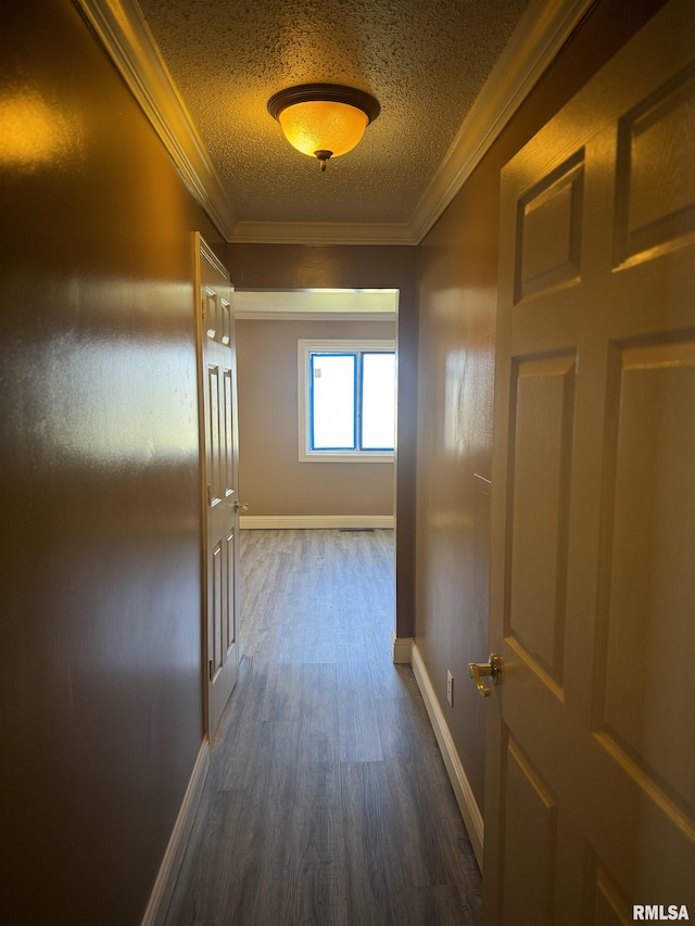 corridor with baseboards, dark wood-type flooring, ornamental molding, and a textured ceiling