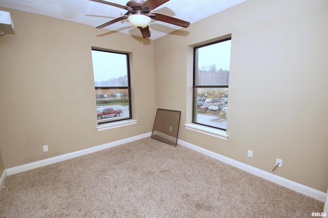 spare room featuring a wealth of natural light, ceiling fan, and light carpet