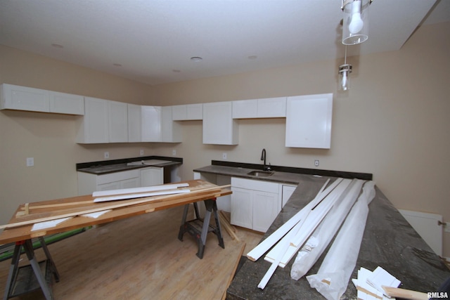 kitchen featuring white cabinets, pendant lighting, light hardwood / wood-style floors, and sink