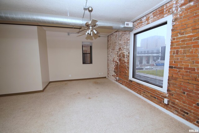 carpeted empty room featuring ceiling fan, brick wall, and a textured ceiling