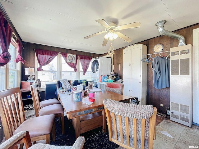 dining space with ceiling fan and wooden walls