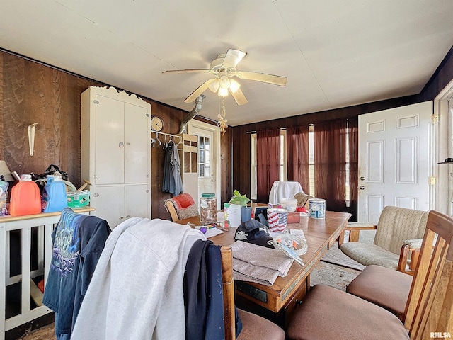 dining room featuring ceiling fan and wooden walls