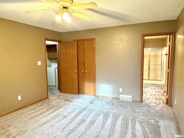 unfurnished bedroom featuring a textured ceiling, ceiling fan, light colored carpet, and washer / dryer