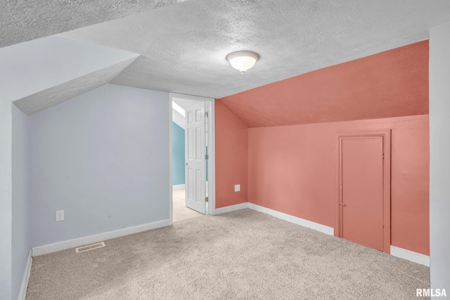 additional living space with a textured ceiling, light colored carpet, and lofted ceiling