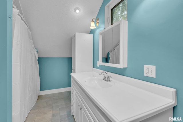 bathroom with a textured ceiling, vanity, and vaulted ceiling