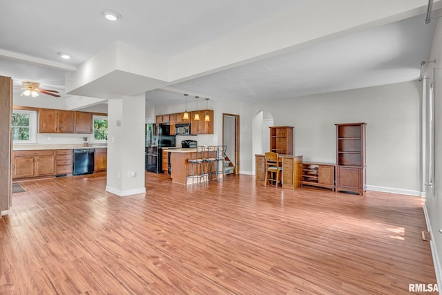 living room with ceiling fan, beamed ceiling, and light hardwood / wood-style floors