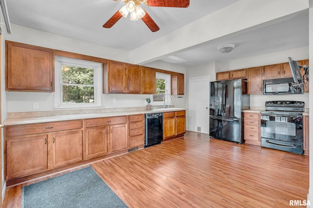 kitchen with ceiling fan, sink, black appliances, beam ceiling, and light hardwood / wood-style flooring