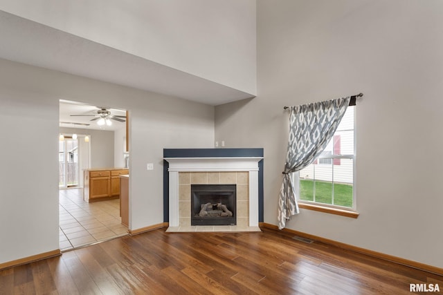 unfurnished living room featuring ceiling fan, plenty of natural light, light hardwood / wood-style floors, and a tile fireplace