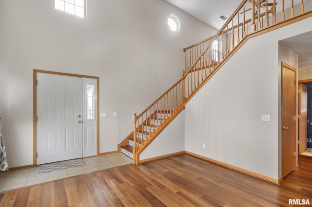 foyer with wood-type flooring and high vaulted ceiling